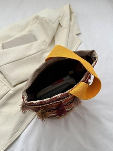 Dettaglio della borsa etnica a secchiello con uncinetto geometrico e frange rosse