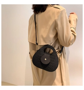 Détail d'un sac selle noir à motif crocodile avec des finitions dorées élégantes