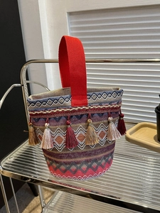 Dettaglio della borsa etnica ricamata con nappe di seta colorate e manici rossi