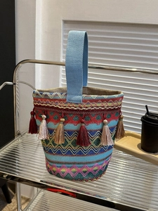 Primo piano della borsa a secchiello etnica intrecciata con motivi geometrici e nappe