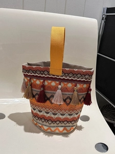 Dettaglio di borsa a mano intrecciata multicolore con motivi etnici e nappe di frangia