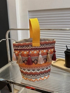 Dettaglio della borsa etnica intrecciata con nappe colorate e motivi geometrici
