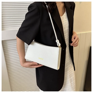 Detalle del bolso de cuero sintético blanco con logo dorado y correa con nudo elegante