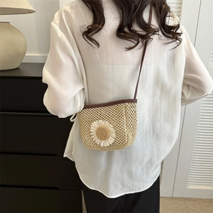 Minimalistische beige strooien emmertas met madeliefje gedragen als crossbody