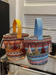Dettaglio di borse a secchiello etniche con motivi a onde colorate e decorazioni nappe