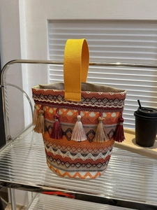 Dettaglio borsa etnica intrecciata con motivi geometrici colorati e nappe decorative