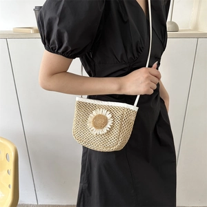 Minimalistische beige strooien emmertas met witte madeliefje op model in zwarte jurk