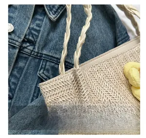 Detail of woven tote bag with braided handle and yellow fabric flower accent
