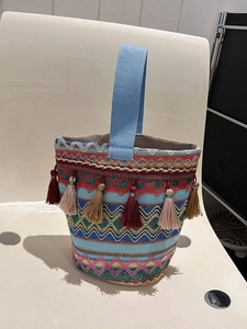 Dettaglio borsa a secchiello etnica colorata con motivi intrecciati e nappe boho