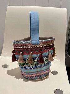 Dettaglio di borsa a secchiello etnica tessuta a mano con motivi geometrici e nappe colorate