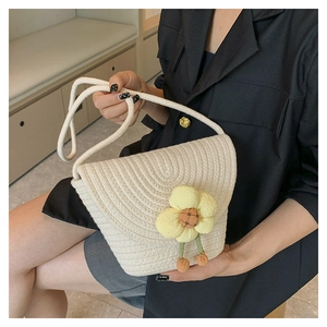 Detail van een witte geweven crossbodytas met gele bloem en oranje kwastjes eraan