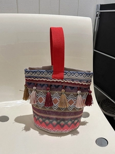 Dettaglio della borsa a secchiello boho con motivi intrecciati colorati e nappe vivaci
