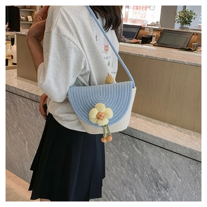 Detail van blauw-wit geweven crossbodytas met bloemdecoratie en smalle schouderriem