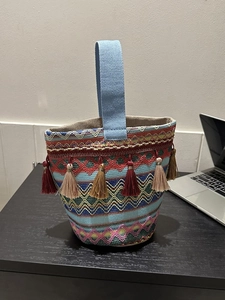Dettaglio della borsa a secchiello etnica colorata con motivi intrecciati e nappe morbide