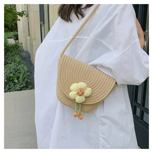 Detalle de bolso bandolera de paja tejida con flor amarilla 3D y correa de hombro tejida