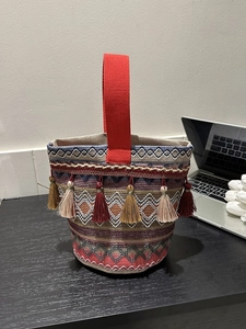 Dettaglio della borsa etnica in maglia con motivi geometrici colorati e nappe