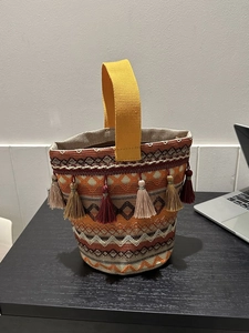 Dettaglio della borsa a secchiello etnica con nappe colorate e trama geometrica