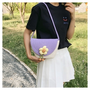 Detalle de un bolso de concha tejido a mano con diseño floral morado y bandolera