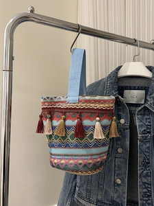 Dettaglio della borsa a secchiello etnica con motivi geometrici colorati e nappe