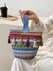 Dettaglio di borsa boho intrecciata con motivi geometrici colorati e nappe decorative