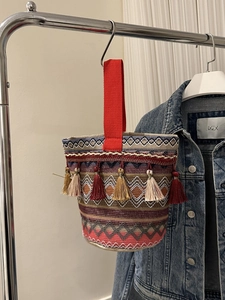 Dettaglio borsa a secchiello tessuta in stile boho con ricami e nappe colorate