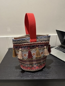 Dettaglio borsa etnica intrecciata con motivi geometrici colorati e nappe decorative
