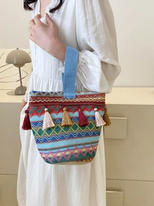 Dettaglio della borsa tote tessuta con motivi geometrici colorati e nappe decorative