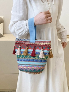 Dettaglio borsa a secchiello boho con motivi etnici colorati e nappe con frange vivaci