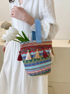 Dettaglio della borsa in tessuto colorato con motivi geometrici e ciondoli a nappa