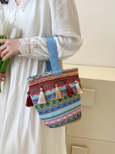 Dettaglio della borsa a secchiello intrecciata boho con motivi a onde e nappe colorate
