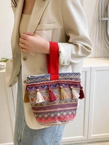 Dettaglio borsa tessuta boho con frange colorate e manico in tessuto rosso di alta qualità