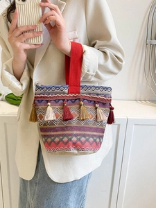 Dettaglio borsa etnica intrecciata con nappe decorative e motivi geometrici colorati