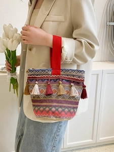 Dettaglio del ricamo etnico colorato e delle nappe decorative sulla borsa a mano tessuta