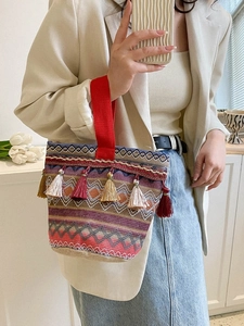 Dettaglio ravvicinato di una borsa etnica intrecciata con nappe colorate e ricami