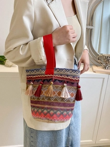 Dettaglio della borsa a mano boho con motivi geometrici colorati e nappe decorative