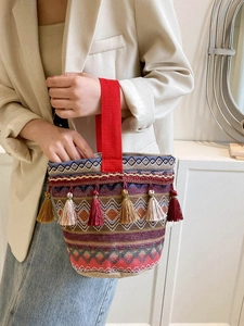 Dettaglio della borsa tote in tessuto geometrico con nappe colorate e manici rossi