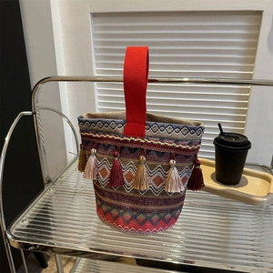 Dettaglio di borsa bohémien colorata con nappe etniche e manico in tela rossa