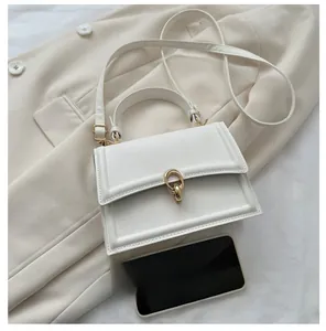 Mini white leather crossbody bag with gold buckle shown next to a phone for size reference