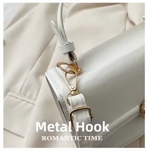 Detailed close-up of golden hardware hook and leather strap on a cream shoulder bag