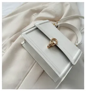 Close-up of the elegant golden double-ring buckle on a white leather handbag