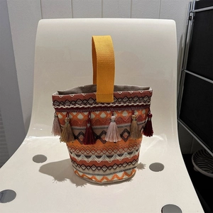 Dettaglio della borsa etnica ricamata con nappe colorate e manico intrecciato giallo