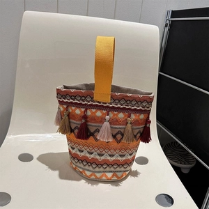 Dettaglio ravvicinato della borsa a secchiello etnica con nappe colorate e motivi tessuti