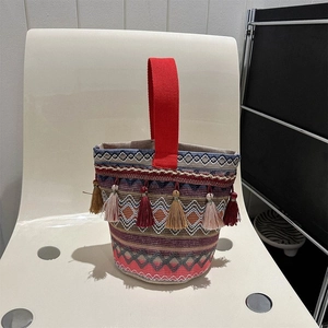 Dettaglio borsa a secchiello etnica con motivi geometrici e nappe colorate vivaci