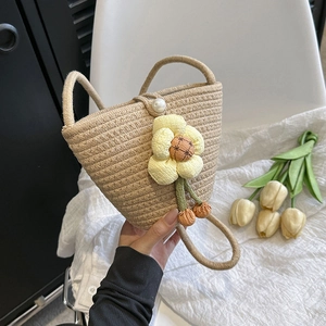 Detail of woven bucket bag featuring large fabric flower charm and pearl buckle clasp