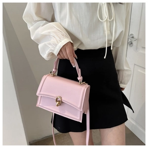 Detail of light pink faux leather crossbody bag with elegant gold metal buckle accent