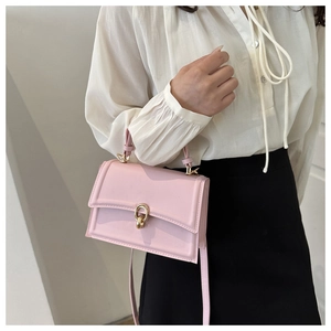 Detail of pink crossbody bag with golden round buckle worn with casual outfit