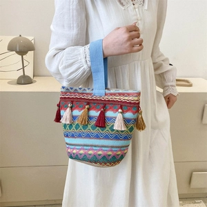 Dettaglio della borsa a secchiello tessuta boho con nappe colorate e ricamo geometrico