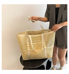 Detail of a large beige mesh beach tote bag featuring reinforced straps and durable texture