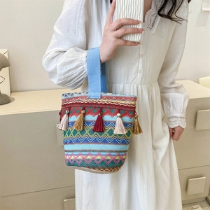 Dettaglio borsa tote boho intrecciata con motivi geometrici colorati e nappe decorative