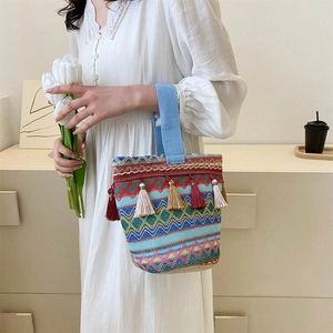 Dettaglio della borsa a secchiello etnica intrecciata con nappe e ricami multicolori